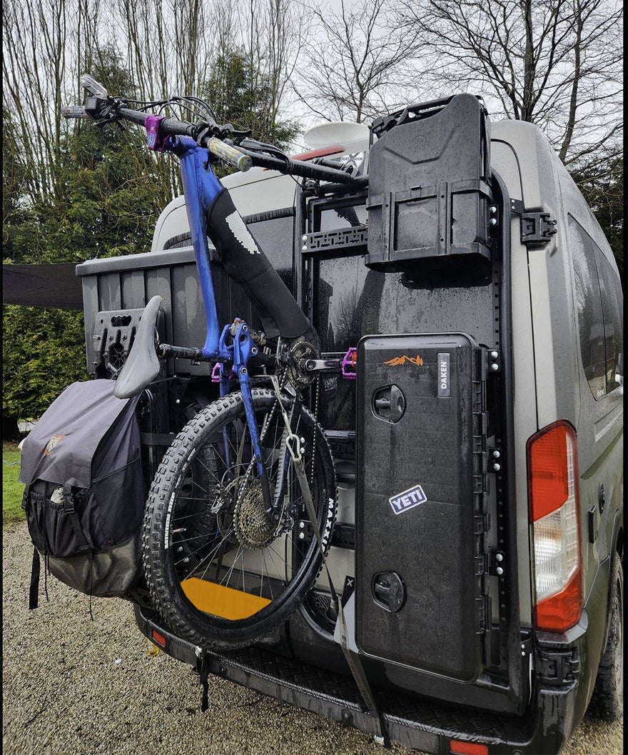 2 bicycles on the rear door of a Ford Custom van