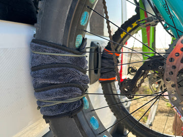 Close-up of a bicycle wheel with a towel wrapped around it, on a blurred background.