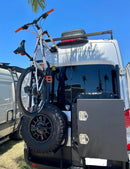 Fork mount bike rack installed on a Ford Transit rear door using the Bike-Hook system. Holds bikes vertically without drilling or a hitch, perfect for campervan travel.

