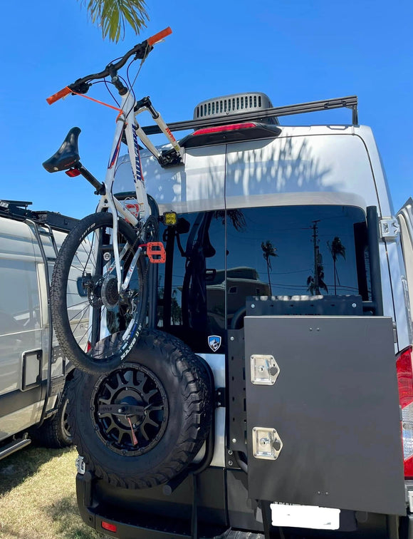 Fork mount bike rack installed on a Ford Transit rear door using the Bike-Hook system. Holds bikes vertically without drilling or a hitch, perfect for campervan travel.

